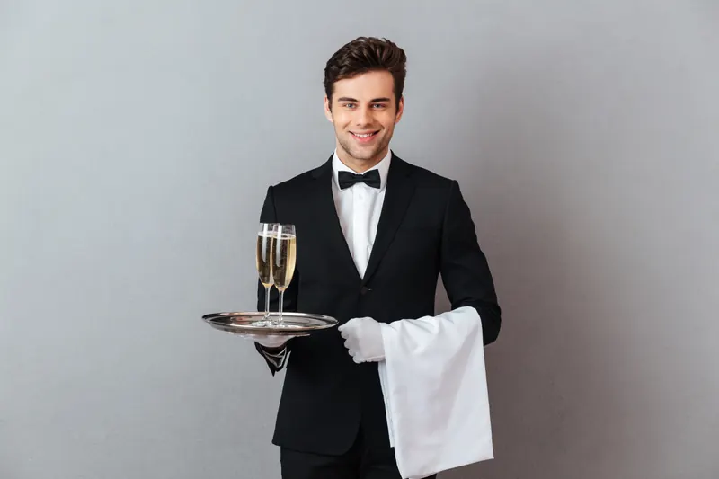 Butler in a tuxedo serving champagne